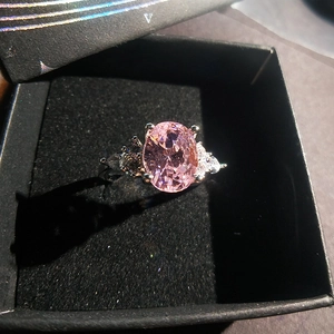 Close-up of rose gold ring featuring a pink oval gemstone and side pear diamonds