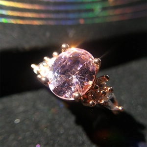 Macro detail of rose gold ring with a sparkling pink gemstone and pavé diamonds