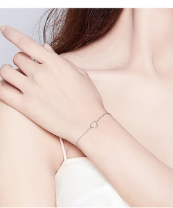 Close-up of a sterling silver chain bracelet with a hollow heart charm on a model's wrist