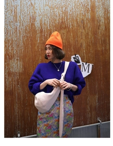 Streetstyle foto van een oranje gebreide muts gecombineerd met een donkerblauwe trui