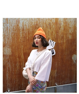 Streetstyle-foto van een oranje gebreide muts met wit T-shirt en artistieke achtergrond