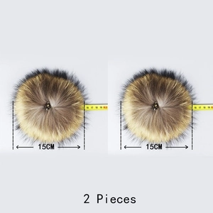 Detail of two 15cm natural raccoon fur pom-poms with metal snap buttons and size markers