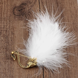 Detail of flamingo brooch with white feathers, pearls, and gold metal on wood