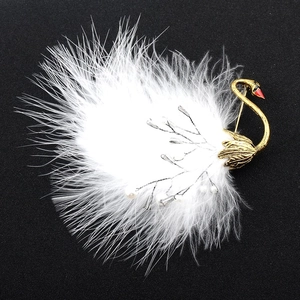 Detailed view of swan brooch with golden metal, white feathers, and pearls