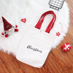 Detail of Christmas canvas tote bag with red handles and elegant script print