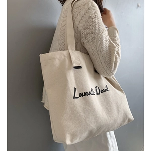 Detail of a large off-white canvas tote bag featuring black Lunatic Devil artistic font