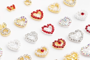 Detailed macro view of assorted heart-shaped nail charms with rhinestones and pearls