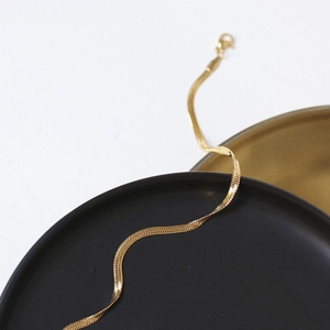 Detail of 18K gold-plated flat snake chain necklace with lobster clasp and mirror finish