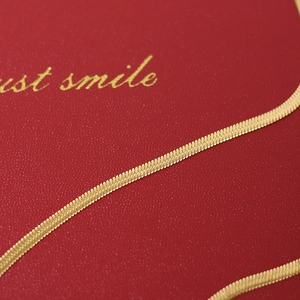 Macro view of gold snake chain texture on dark red leather background with soft light