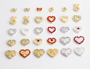 Detail of alloy nail charms with 520 hearts, bows, and crystals on a white background