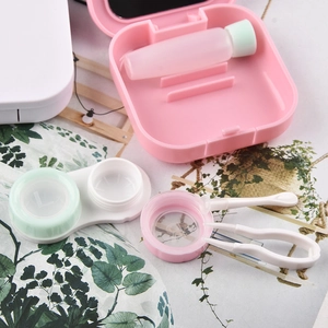 Pink matte square contact lens case set with mirror, solution bottle and tools on green background