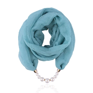 Detailed view of teal chiffon scarf with elegant white pearl and gold metal pendant