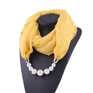 Detail of yellow lightweight chiffon scarf with elegant white faux pearl necklace accessory