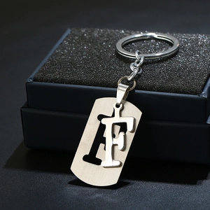 Macro view of silver stainless steel letter F keychain charm in a premium gift box