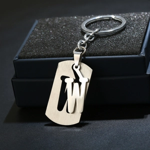 Macro shot of silver letter W keychain with brushed metal texture on a black jewelry box