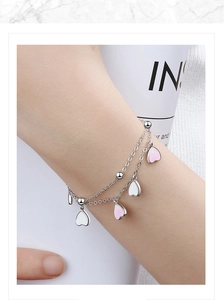 Pink gradient cherry blossom charm bracelet on wrist with silver heart pendants