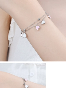 Double-layer silver bracelet featuring pink and white heart charms on a female wrist