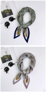 Detail of pleated silk scarves with green and lavender patterns on white background