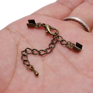 Antique bronze extension chain set with lobster clasp and cord end crimps in palm