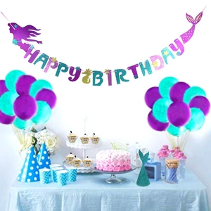 Close-up of mermaid party supplies with glittery banner, balloons and cake toppers