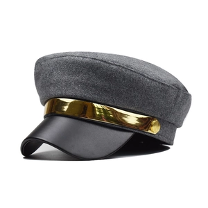 Detailed view of dark grey wool newsboy hat featuring a black leather brim and gold metal band