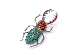 Vue détaillée d'une broche scarabée de luxe avec strass rouges et orange brillants