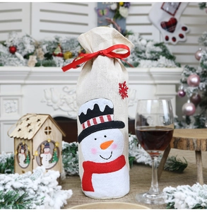 Detailed view of burlap Christmas wine bottle bag with embroidered snowman and red ribbon bow