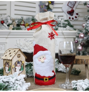 Detail of linen Santa wine bottle cover with red silk ribbon in a cozy holiday setting