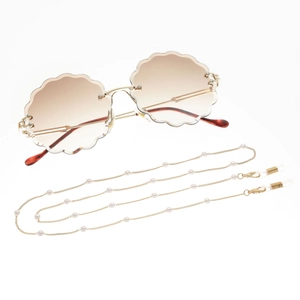Detail of gold eyewear chain with white pearls and gradient round sunglasses