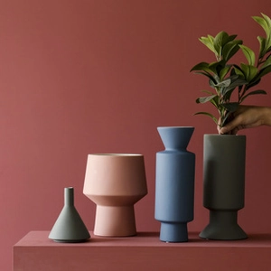Set of four minimalist matte ceramic vases in Morandi colors on a red pedestal