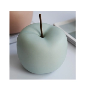 Detalle de manzana decorativa de cerámica verde menta con acabado mate y tallo marrón