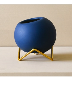 Detail of blue ceramic vase with gold metal tripod stand in minimalist Nordic style