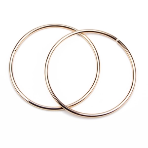 Polished large golden hoop earrings with high-gloss finish on a white background