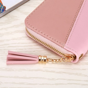 Close-up of pink patchwork leather wallet featuring a gold zipper and tassel detail