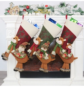 Trois chaussettes de Noël en peluche avec rennes 3D suspendues sur une cheminée festive
