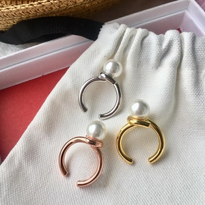 Three twisted pearl rings in silver, gold, and rose gold on a white drawstring pouch