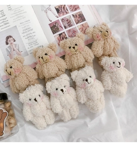 Close-up of cute plush bear charms in white and brown with curly fleece and metal chains