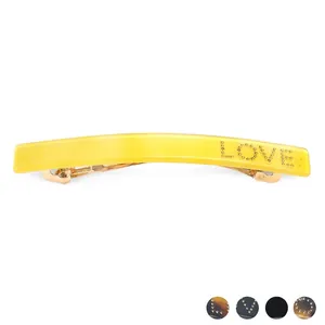 Minimalist rectangular acetate hair clip with golden metal beads spelling LOVE on white base