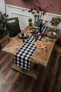 Detailed view of a black and white buffalo plaid table runner on a rustic wooden dining table