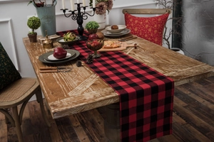 Detailed close-up of red and black checkered table runner on a rustic wooden dining table
