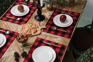 Détail de sets de table à carreaux rouges et noirs sur une table à manger en bois