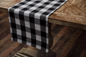 Detail of black and white checkered table runner on a rustic wooden table surface