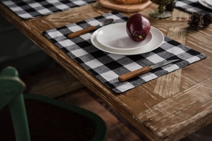 Detailed close-up of a rustic black and white plaid table runner on a wooden surface