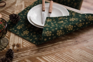 Detail of Christmas green table runner with gold snowflake pattern on rustic wood