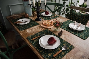 Detail of dark green cotton linen placemats with gold snowflake print for festive dining