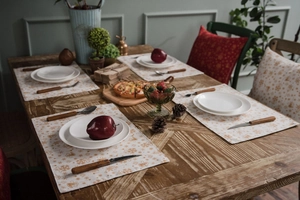 Festive cotton linen placemat with gold foil patterns and elegant cutlery set on wood