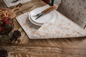 Close-up of festive cotton linen placemats with gold snowflakes and reindeer patterns