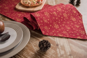 Detail of red Christmas table runner with gold snowflake patterns on rustic wood