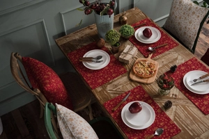 Detailed close-up of red Christmas table runner with golden reindeer and snowflake patterns