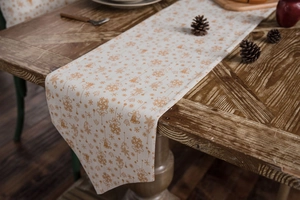 Detail of Christmas table runner with golden snowflakes and bells on wooden table